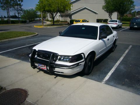 2000 Ford Crown Victoria - White Mercury Grand Marquis fitted with a black push-bumper grille guard, parked diagonally in a residential parking lot with other cars ne…