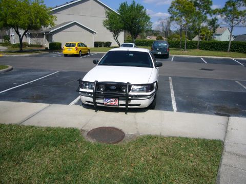 2000 Ford Crown Victoria - A white 2000 Ford Crown Victoria is parked in a lot with other vehicles.