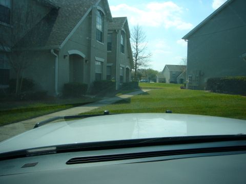 2000 Ford Crown Victoria - View from inside a white vehicle, looking out over the hood towards a residential area.