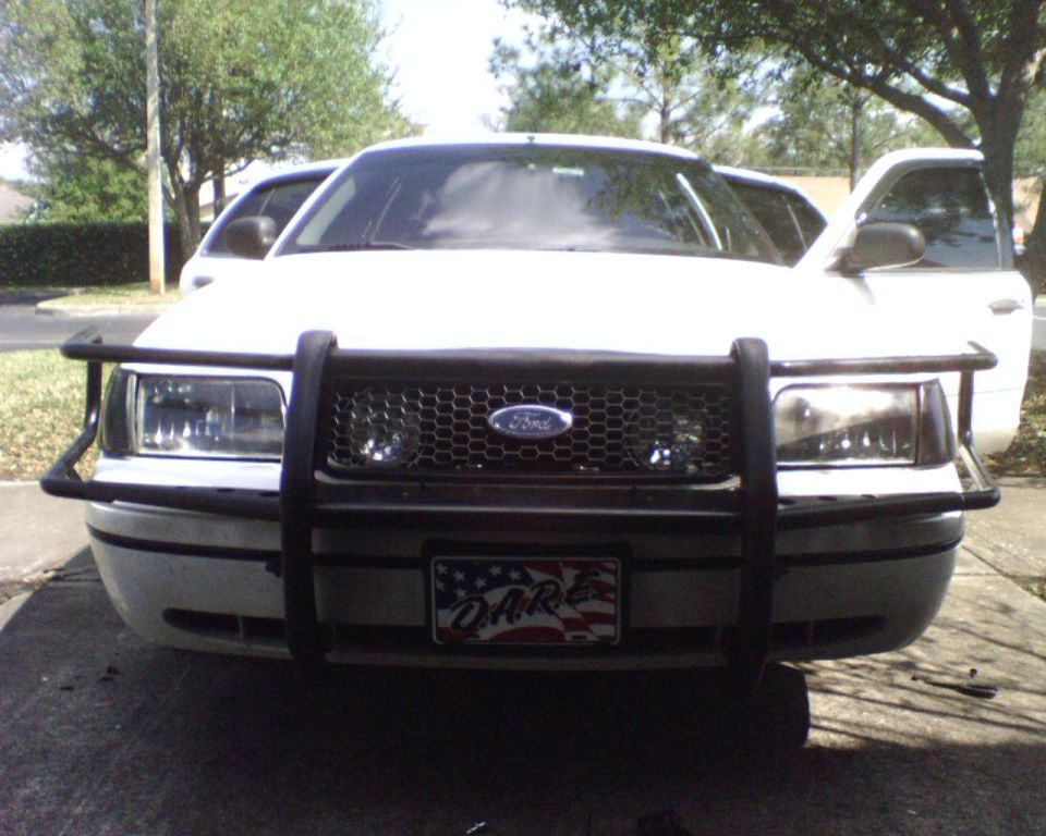 White Ford Crown Victoria front view with black push bar and D.A.R.E. flag front plate