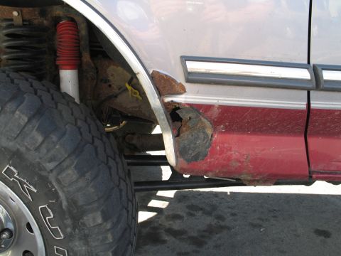 1995 Ford Bronco - This Ford Bronco shows extensive rust damage on its lower body panel near the rear wheel.