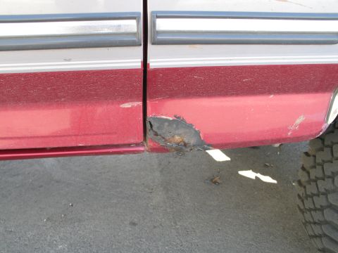 1995 Ford Bronco - The lower body panel of a 1995 Ford Bronco exhibits extensive rust, indicating a need for repair.