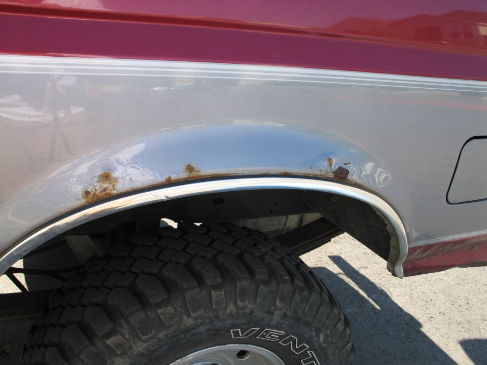 1995 Ford Bronco rear wheel well showing rust on the fender trim and body