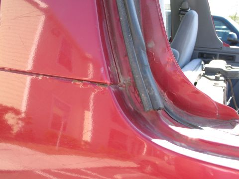 1995 Ford Bronco - Detail shot of the interior seam and rubber seal on a red vehicle, revealing signs of wear and rust.