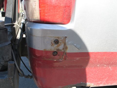 1995 Ford Bronco - Close-up of the rear bumper corner on a 1995 Ford Bronco, highlighting rust damage around the mounting bolts.