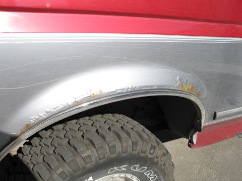 1995 Ford Bronco - Rust is visible around the wheel well of this 1995 Ford Bronco's silver and red body.
