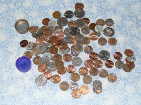 1995 Ford Thunderbird - A collection of various coins and two bottle caps are scattered across a patterned surface.