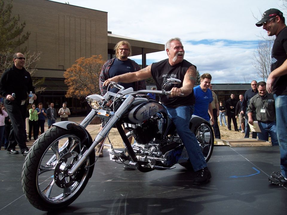 Man sitting on a custom chopper motorcycle at an outdoor event