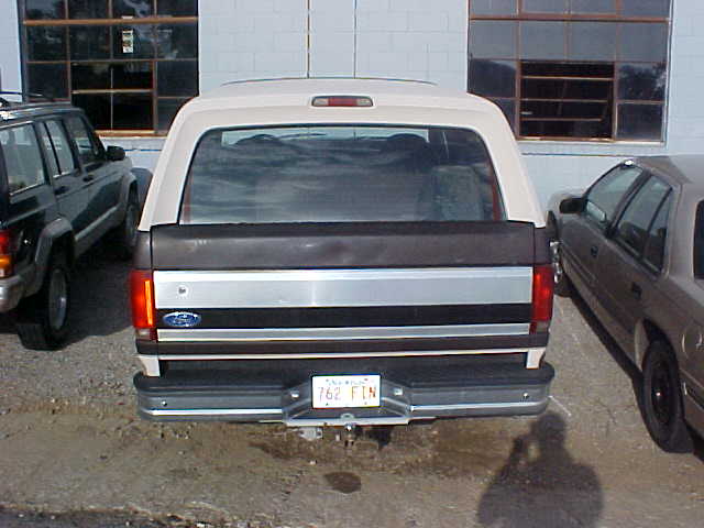 Rear view of black and tan Ford Bronco with tailgate and spare tire, plate reads 762 FIN