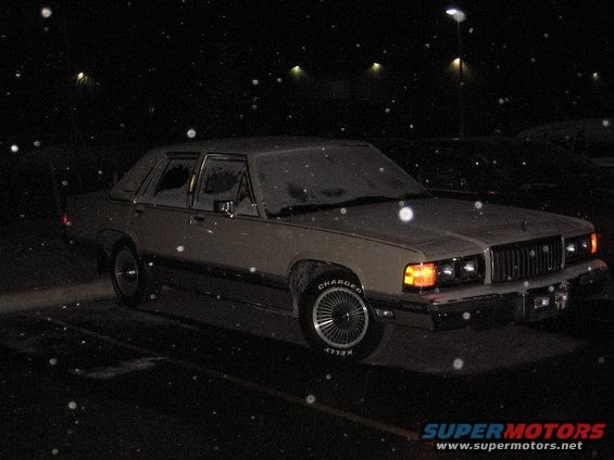 1988 Mercury Grand Marquis sedan in tan, covered in snow, parked at night