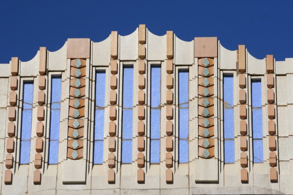 Building facade with geometric patterns and blue windows against a clear blue sky