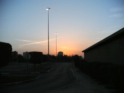 1999 Mercury Grand Marquis - A street scene unfolds at dusk, with tall light poles and distant buildings silhouetted against the colorful sunset sky.