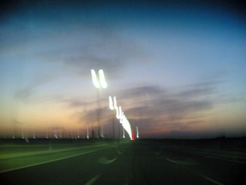 1999 Mercury Grand Marquis - The road ahead is blurred with streaks of light from street lamps and distant vehicle lights at twilight.