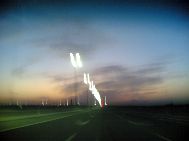 Highway at dusk with blurred lights from street lamps and car taillights