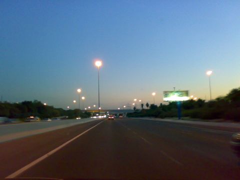 1999 Mercury Grand Marquis - A view from a vehicle on a highway at dusk, with streetlights illuminating the road and a billboard visible in the distance.