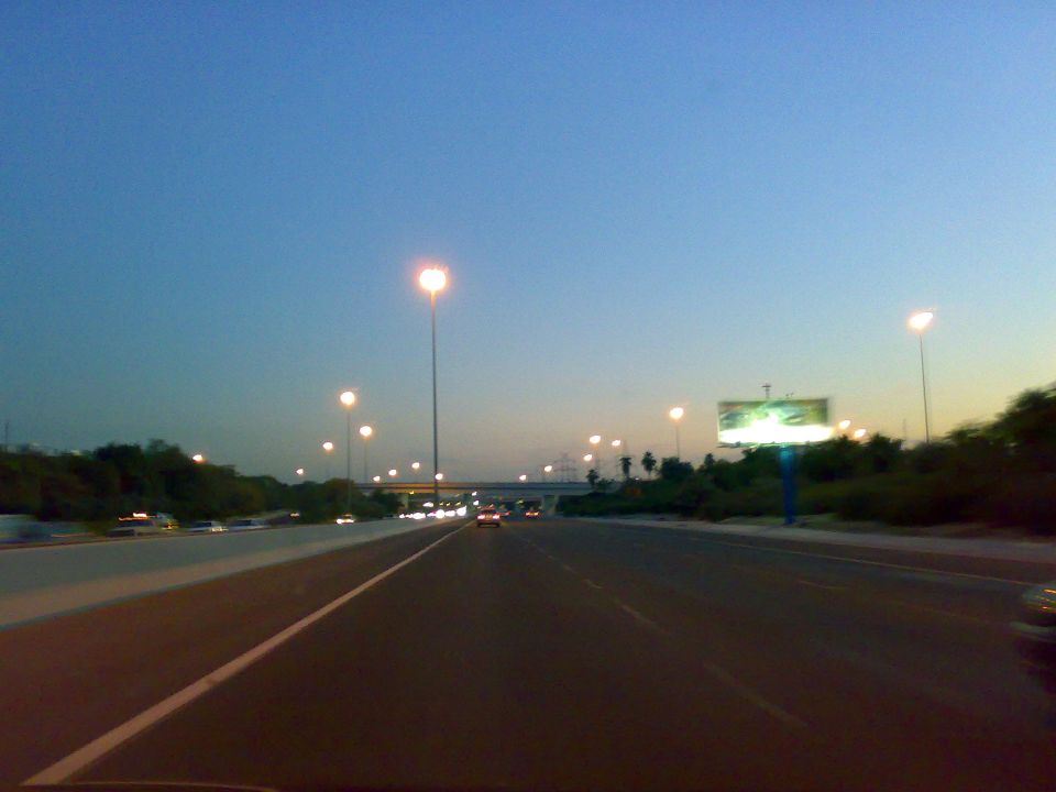 Highway scene at dusk with streetlights and a billboard