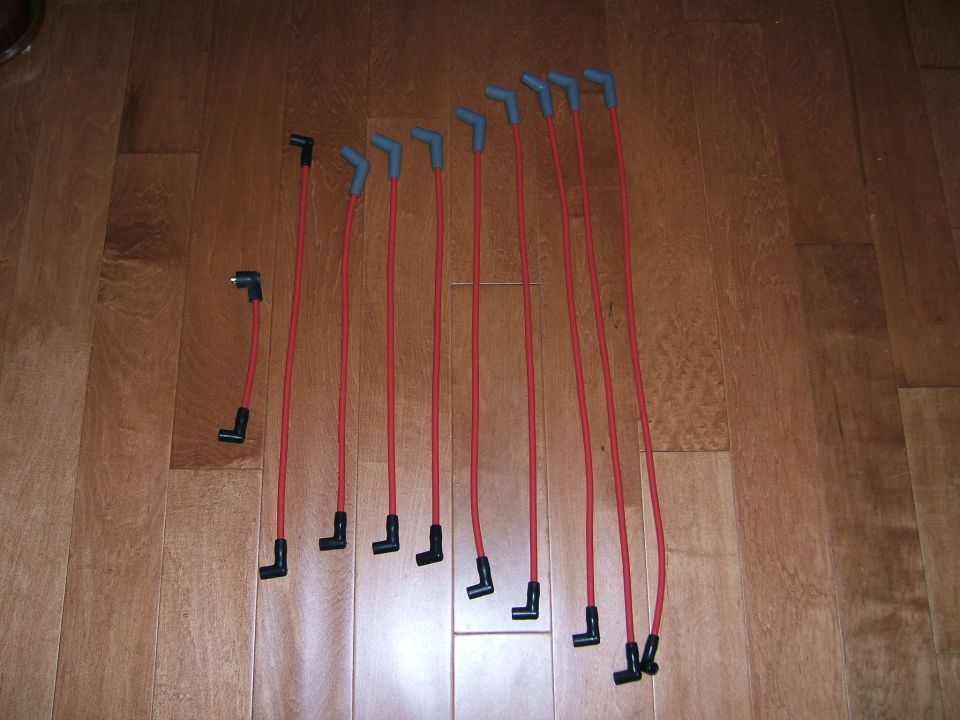 Set of red spark plug wires laid out on a wood floor
