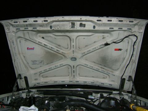 1991 Ford Bronco - The underside of a vehicle's hood is shown, revealing engine parts and various stickers.