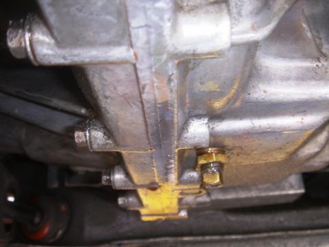 1991 Ford Taurus - Close-up of a vehicle's transmission or oil pan, showing a drain plug and surrounding metal components.