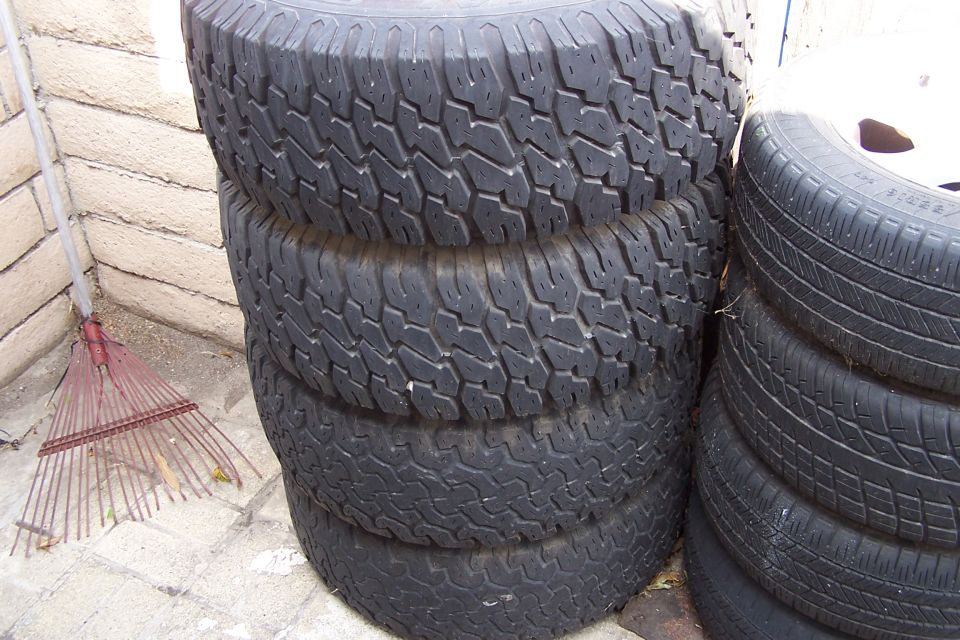 stack of four tires, one on its side, next to a rake