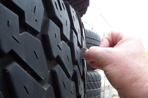 1990 Ford Bronco - A coin is used to measure the tread depth of a tire, indicating it is for sale.