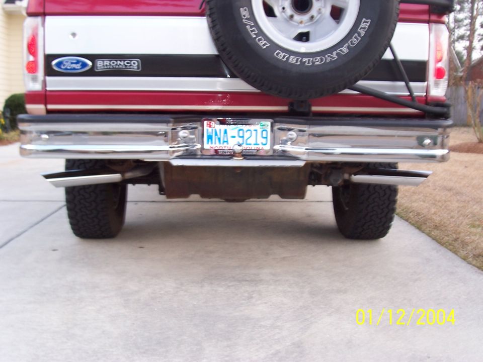 Rear view of a red Ford Bronco with dual exhaust pipes and a spare tire mounted on the back
