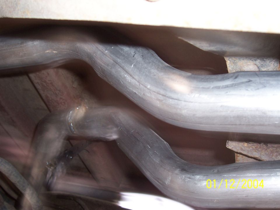 Underside view of dual exhaust pipes, one bent sharply