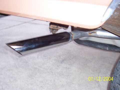 1994 Ford Bronco - Close-up of a vehicle's chrome exhaust pipe, showing custom welding and a tan body panel above.