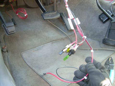 1988 Ford Bronco - This photo shows a hand working on aftermarket wiring and switches in a vehicle's interior.