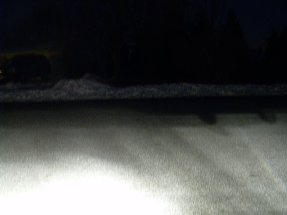dark snowy scene with headlights on, supermotors.net logo in corner