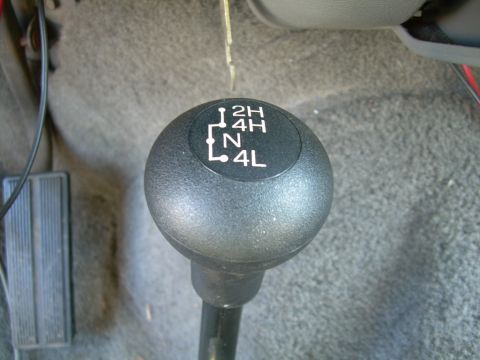 1988 Ford Bronco - Close-up of a black transfer case shift knob with a white shift-pattern diagram showing 2H, 4H, N and 4L positions, mounted on a gray carpe…