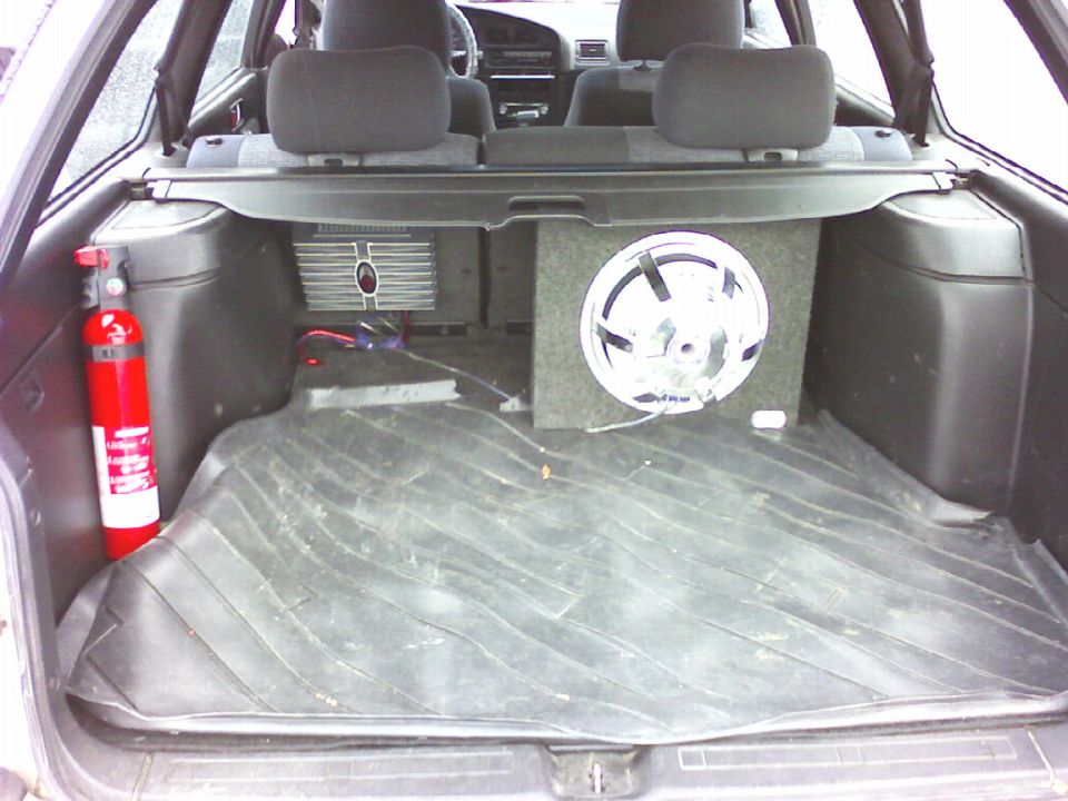 Rear cargo area of a wagon with a subwoofer and fire extinguisher