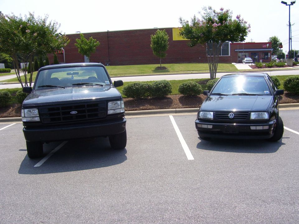 Black Ford truck and black Volkswagen Jetta parked in a lot