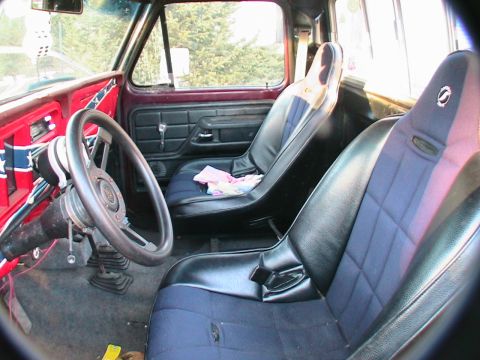 1977 Ford F-250 - The interior of a truck features racing bucket seats and a custom steering wheel.