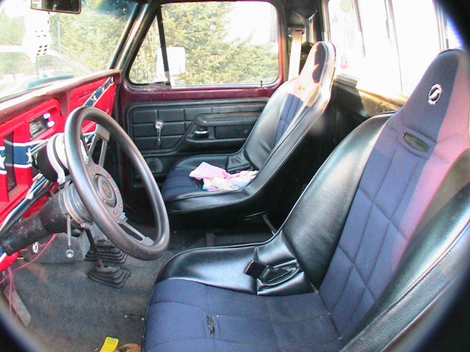 Truck interior with racing seats, aftermarket steering wheel, and a rebel flag decal on the dash