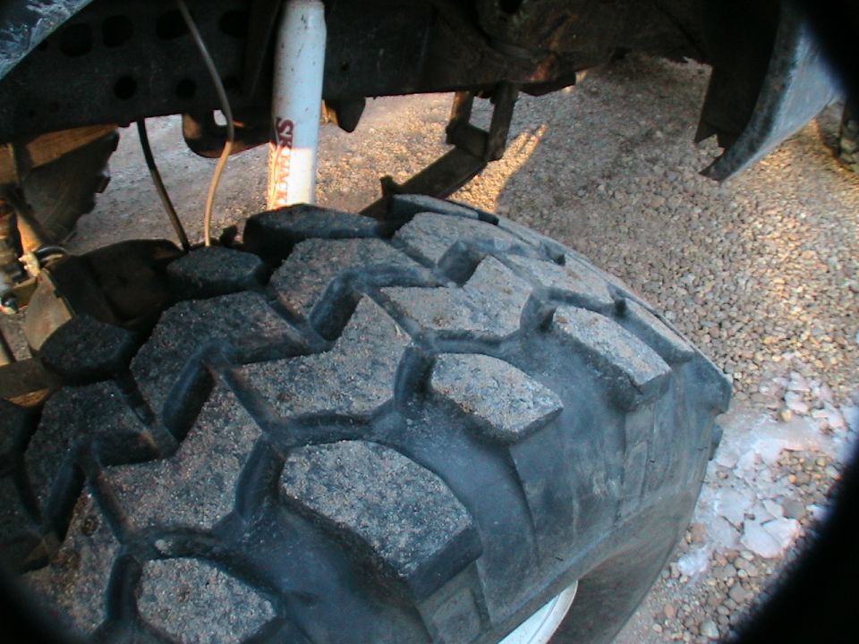 Close-up of a large, knobby off-road tire and suspension components of a truck