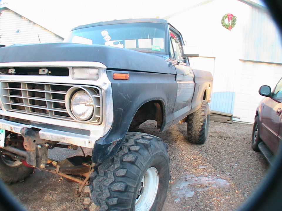 1977 Ford F-250 pickup truck, lifted, dark blue, front 3/4 view, chrome grille, large off-road tires