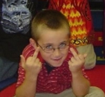 1990 Ford Bronco - A young child wearing glasses and a red shirt gives the middle finger with both hands.