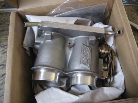 1989 Ford Bronco - A new BBK 'Power-Plus' twin 58mm cast-aluminum throttle body sitting in its cardboard box on white tissue paper, with gold-plated throttle…
