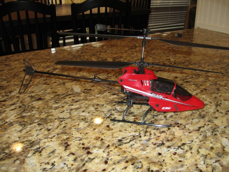Red remote-controlled helicopter with "BLADE" text on its side, resting on a granite countertop