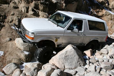 1996 Ford Bronco - A white 1996 Ford Bronco is shown maneuvering over a challenging rocky terrain.