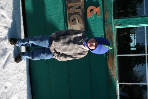 1996 Ford Bronco - A child stands in the snow next to a weathered green building with a window.
