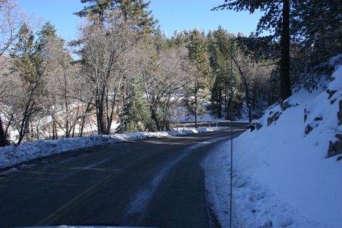 1996 Ford Bronco - A winding road through a snowy mountain landscape with trees lining the route.