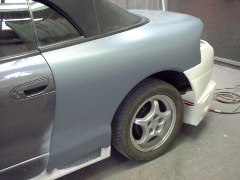 1994 Ford Probe - A car is undergoing bodywork, with primer applied to the rear fender and door.