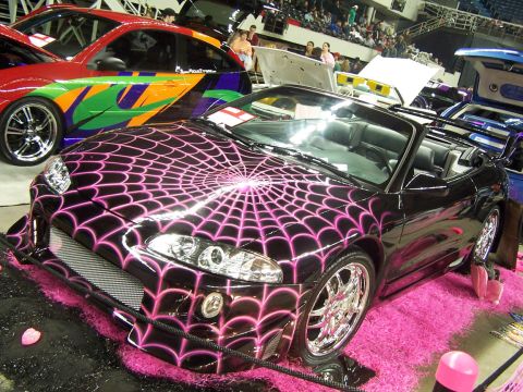 1994 Ford Probe - A custom black convertible with a striking pink spider web graphic design is displayed indoors.