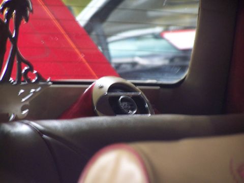 1994 Ford Probe - The interior of a car shows a chrome exhaust tip and red trim, with other vehicles seen through the rear window.