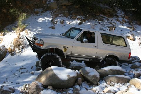 1996 Ford Bronco - A 1996 Ford Bronco navigates a rocky, snow-covered trail.