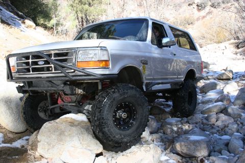 1996 Ford Bronco - Silver 1996 Ford Bronco tackling a rocky trail with snow patches.