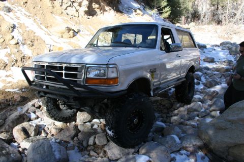 1996 Ford Bronco - A modified silver Ford Bronco navigates a rocky, snow-dusted stream bed.