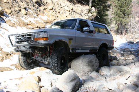 1996 Ford Bronco - Modified 1996 Ford Bronco tackling a challenging rocky trail with snow patches.